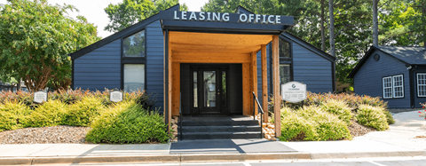 a black building with a wooden door and a sign that reads leasing office